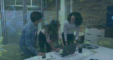 Colleagues reviewing financial charts on laptop in modern industrial office