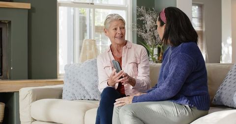 Senior women enjoying candid conversation on sofa