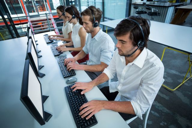 Business executives with headsets using computer in office