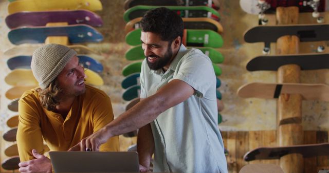 Image of happy diverse male skateboarders fixing skateboard in skate shop. Skateboarding, sport, hobby and skate shop concept.