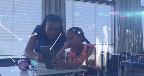 Teacher guiding student through tablet in tech-enhanced classroom