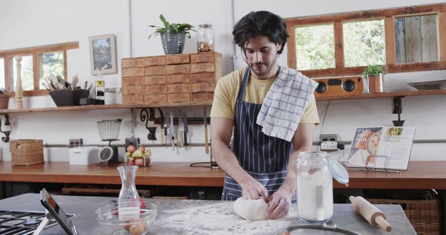 Man kneading dough in home kitchen, ideal for culinary blogs, cooking tutorials, recipe websites, or food magazines. This scene highlights the process and craftsmanship involved in baking, offering a warm, authentic kitchen setting.