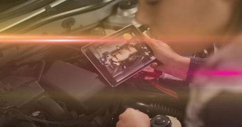 Auto technician using tablet for engine diagnostics and fluid inspection in garage