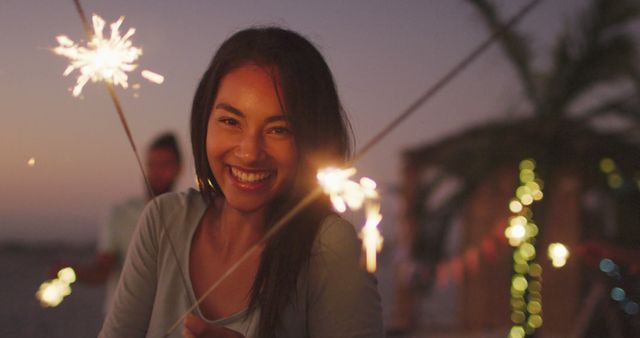 Joyful Woman Enjoying Beach Party with Sparklers at Sunset - Download Free Stock Images Pikwizard.com