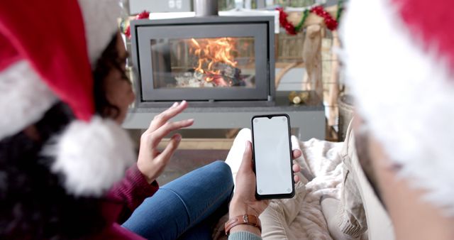 Couple Using Smartphone in Cozy Christmas Setting by Fireplace - Download Free Stock Images Pikwizard.com