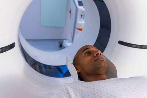 African american man undergoing ct scan in scanner bore wearing immobilizer and gown