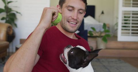 Smiling Man Playing with Adorable Dog Indoors for Quality Time