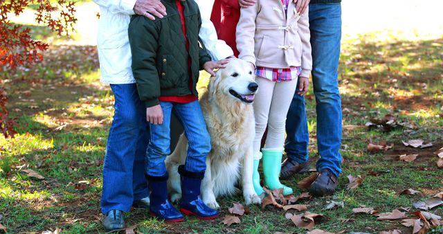 Family outdoors in autumn park, walking with golden retriever. Children wearing boots, standing on leaf-covered grass. Suitable for themes of family bonding, outdoor activities, autumn season, pet companionship, and childhood memories.