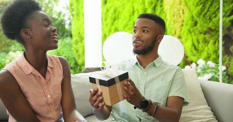 Young Couple Exchanging Gifts Smiling on Patio