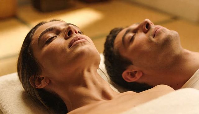 Couple relaxing side by side on spa treatment tables in warm golden light