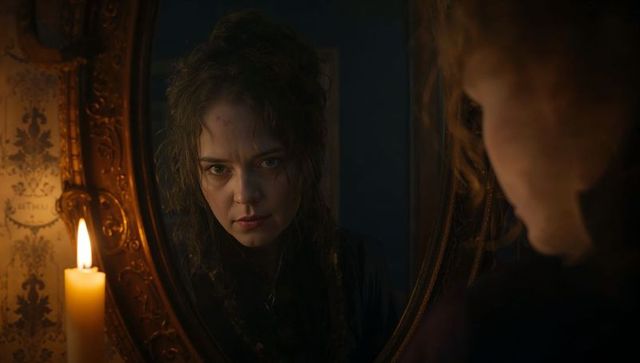 Victorian woman reflects in candlelit mirror