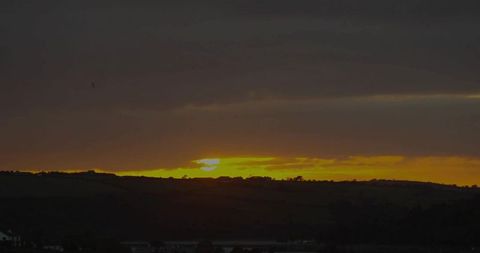 Glowing Sunset Over Rural Valley with Hill Silhouettes