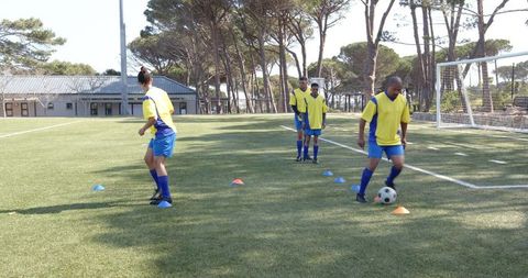 Soccer players practicing dribbling skills on sunny field