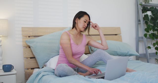 Young Woman Concentrating While Working on Laptop in Bed - Download Free Stock Images Pikwizard.com