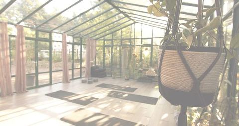 Sunlit conservatory hanging woven planter with yoga mats and meditation cushions