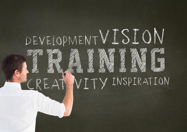Man writing on a chalkboard featuring words like 'development', 'vision', 'training', 'creativity', and 'inspiration'. Perfect for education, business training, coaching, or motivational contexts, promoting professional development and learning.