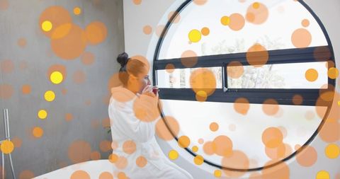 Woman relaxing in modern spa bathroom gazing through round window
