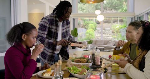 Diverse Family Carving Roast and Sharing Feast at Modern Sunlit Dining Table