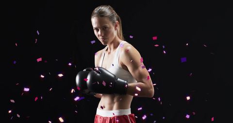 Confetti falling on caucasian female boxer celebrating victory