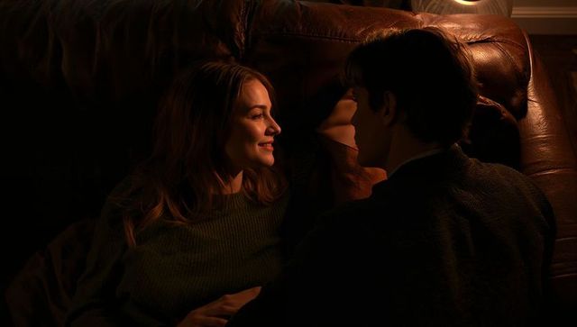 Couple sharing intimate evening on leather sofa with warm lamp glow and cozy knit sweaters
