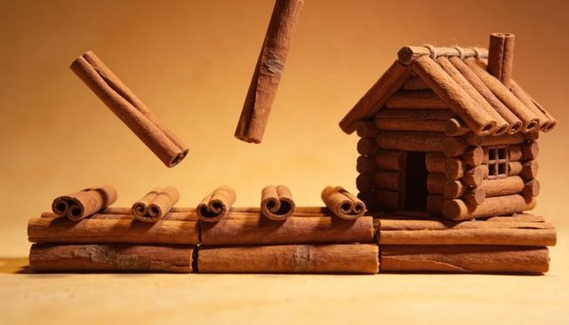 Displaying handcrafted cinnamon stick log cabin on platform with suspended cinnamon quills