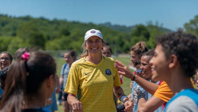 Smiling female soccer coach guiding youth team during outdoor training and team building