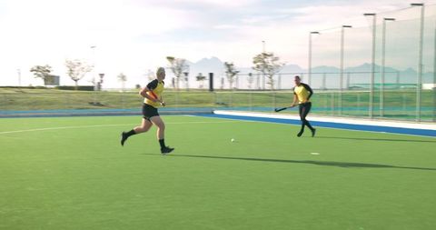 Teammates running with hockey sticks on turf