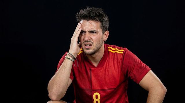 Frustrated soccer fan holding head wearing red number 8 jersey showing intense emotion