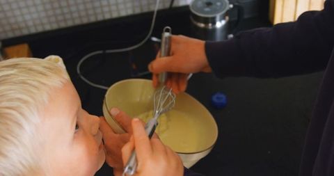 Father and Son Whisking Batter Together in Kitchen