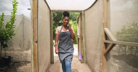 Horticulturist Using Phone in Eco-Friendly Garden Nursey