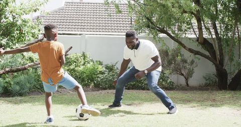 Father and Son Playing Soccer in Sunny Backyard Enjoying Leisure Time