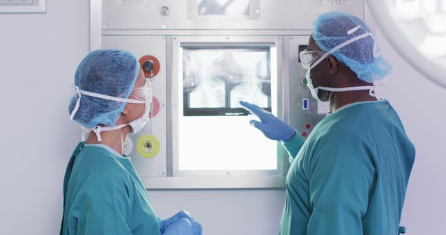 Image of diverse male and female surgeon studying x-ray before operation in operating theatre. Hospital, medical and healthcare services.