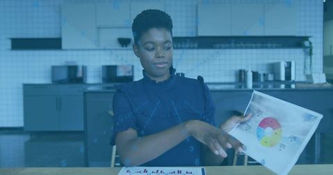 Businesswoman presenting pie chart and pointing to bar chart in modern office kitchenette