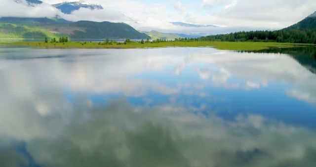 Beautiful scene of a mountain lake with calm waters reflecting the sky and clouds. Suitable for themes of tranquility, nature, outdoor adventures, and landscapes. Ideal for travel websites, nature documentaries, blogs focused on relaxation and meditation, or background images for social media posts.