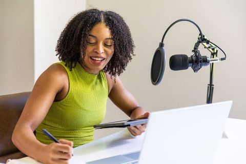 African american content creator recording podcast in home studio taking notes