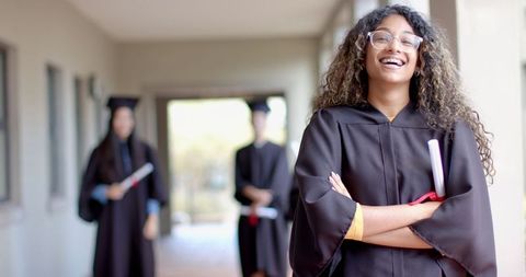 Confident Young Graduate Smiling in Hallway with Fellow Graduates - Download Free Stock Images Pikwizard.com