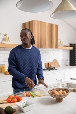 African American Man Whisking Eggs in Modern Bright Kitchen