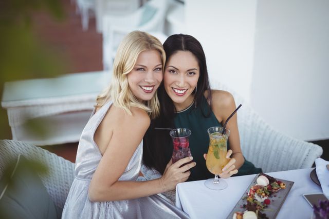Portrait of smiling womens holding cocktail glass at restaurant