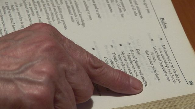 Close-up scene shows a person reading from the Book of Psalms in a Bible, highlighting a hand gently touching the scripture. Perfect for conveying themes of spirituality, meditation, or study. Ideal for religious content, sermons, educational materials, or promotional religious events.