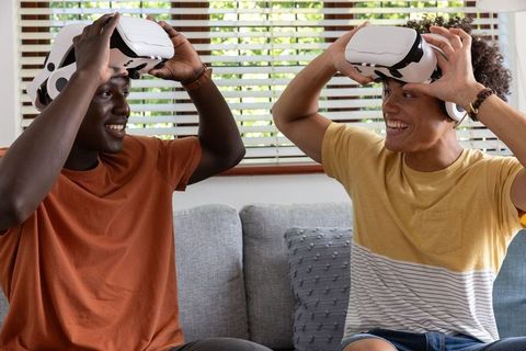Two friends relaxing with vr headsets on living room sofa