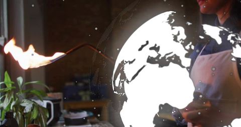 Mid-adult woman using blowtorch with holographic globe overlay for modern culinary tech