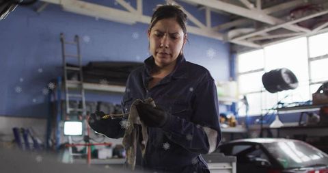 Female mechanic checking oil level in busy garage