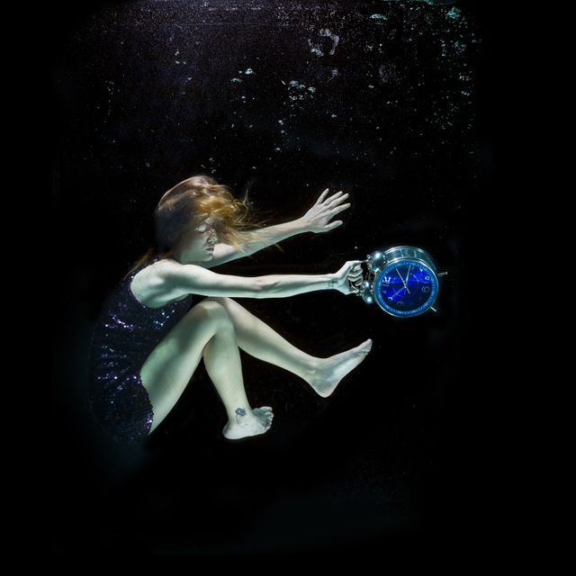 Woman floating underwater holding a large clock, creating a surreal and dreamy atmosphere. Useful for projects involving time, fantasy, or mysterious themes. Ideal for artistic expressions, conceptual designs, and imaginative storytelling.