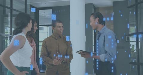 Team discussing strategy in modern office lobby with tablet and digital overlay