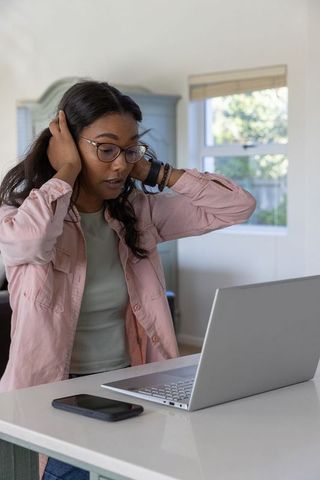 Stressed Woman Working Remotely on Laptop in Home Office Environment