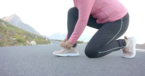 Woman Tying Shoelaces Preparing for Morning Hike in Mountains
