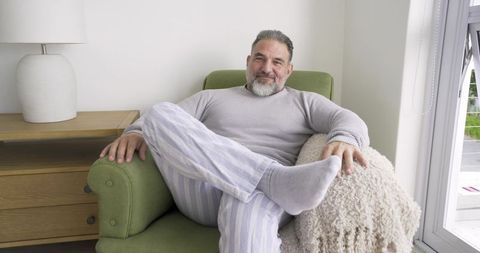 Senior man relaxing in cozy home setting with striped lounge pants