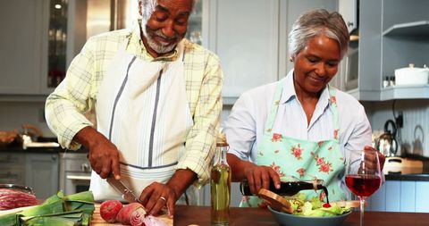 Senior Couple Joyfully Preparing Salad Together in Kitchen