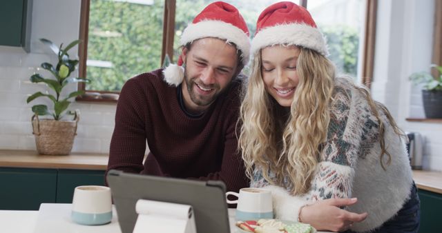 Couple Enjoying Holiday Video Call with Santa Hats in Cozy Kitchen - Download Free Stock Images Pikwizard.com