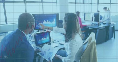 Collaborative team analyzing financial charts and data visualization on multiple screens